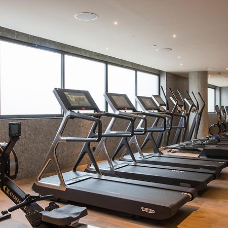 호텔 소피아 바르셀로나 - 인 더 언바운드 컬렉션 바이 하얏트 외부 사진 The photo shows a modern gym space featuring several pieces of exercise equipment. In the foreground, there are treadmills, while in the background, there are elliptical machines lined up against large windows that provide natural light. The flooring