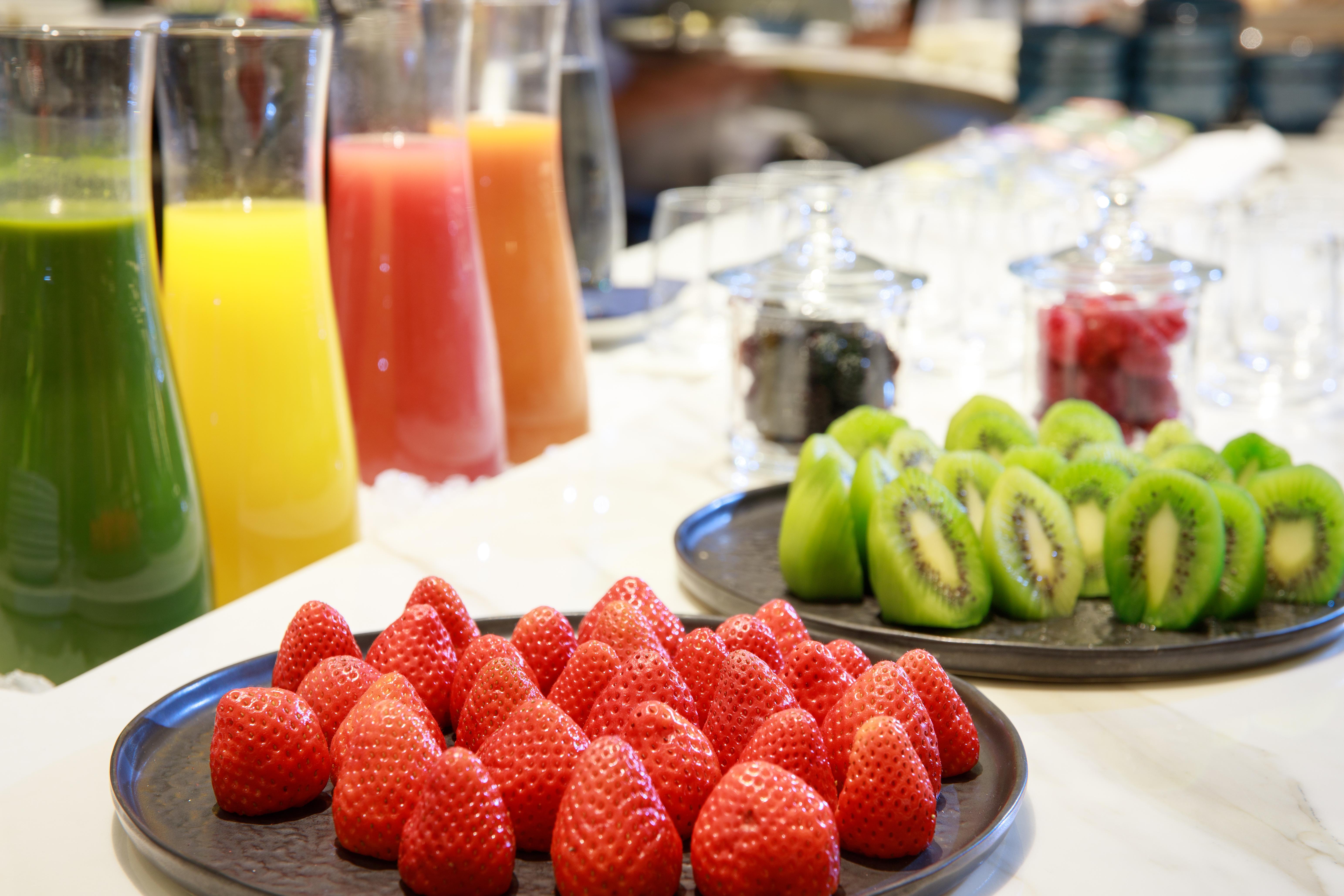 호텔 소피아 바르셀로나 - 인 더 언바운드 컬렉션 바이 하얏트 외부 사진 The photo displays a vibrant assortment of fresh fruits and juices. In the foreground, there is a plate of bright red strawberries neatly arranged. Behind the strawberries, there are several tall glasses filled with various juices, including orange, 