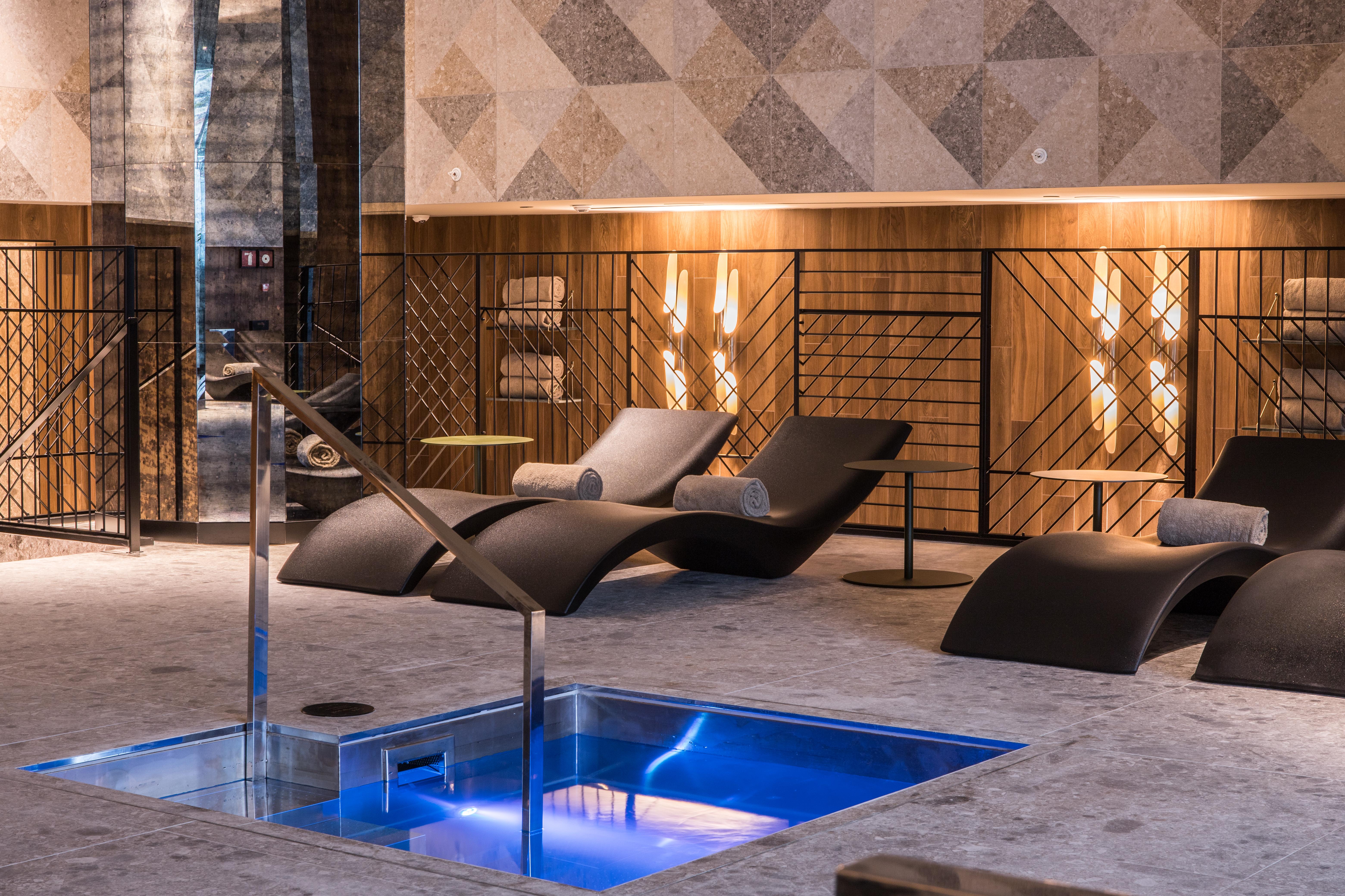 호텔 소피아 바르셀로나 - 인 더 언바운드 컬렉션 바이 하얏트 외부 사진 The photo shows a modern spa or relaxation area. In the foreground, there is a small rectangular pool of water with a sleek metal railing. Surrounding the pool are comfortable lounge chairs, designed for relaxation, likely positioned for users to unw